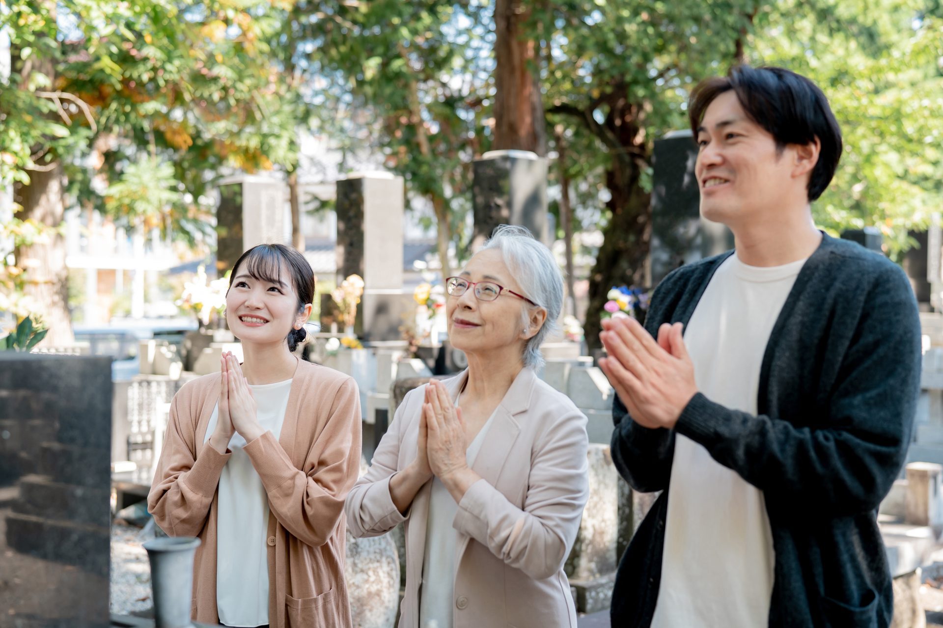 墓前で家族が手を合わせている様子